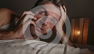 Close up face portrait of sleepless and awake attractive man with eyes wide open at night lying on bed suffering insomnia sleeping