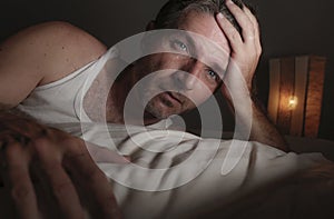 Close up face portrait of sleepless and awake attractive man with eyes wide open at night lying on bed suffering insomnia sleeping