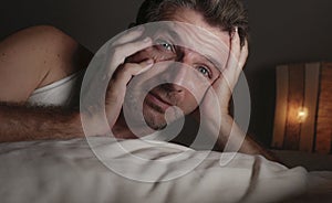 Close up face portrait of sleepless and awake attractive man with eyes wide open at night lying on bed suffering insomnia sleeping