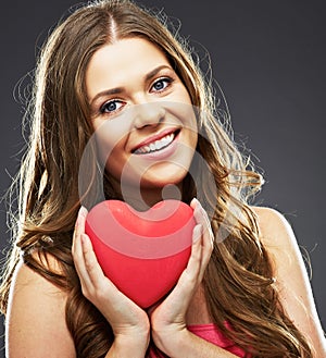 Close up face portrait of smiling woman holding red heart.