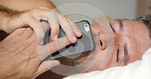 Close up face portrait of young attractive and happy man lying on bed using mobile phone kissing the cellular happy and cheerful
