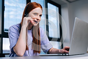 Close-up face of pretty young woman operator using headset and laptop during customer support at home office.