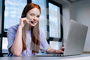 Close-up face of pretty young woman operator using headset and laptop during customer support at home office.