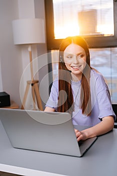 Close-up face of pretty young woman operator using headset and laptop during customer support at home office.