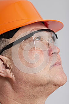 Face profile of thoughtful plump engineer in protective glasses, construction worker in hard hat onstudio background