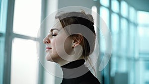 Close-up of face of quiet young woman closing eyes against the window.