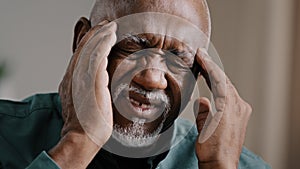 Close-up face sad elderly african american man feeling headache chronic migraine unhealthy multiracial grandpa massaging