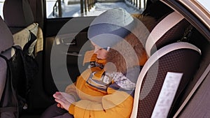 Close- up of the face of a sad little boy in the car in the car seat in winter