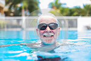 Close up of face of senior or mature man swimming and having fun at the pool - training and enjoy alone