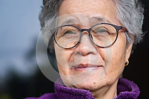 Close-up of face senior woman with short gray hair, wearing glasses, smiling and looking at the camera. Concept of aged people