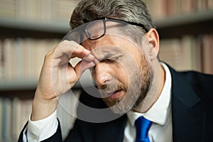 Close up face of stressed man with headache migraine. Headache, tiredness and stress. Man in suit uses a laptop, is