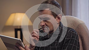 Close-up face of tired Caucasian man taking off eyeglasses and looking away thinking. Focused middle aged businessman