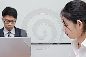 Close up face of unhappy Asian business woman having conflict with her colleague in office.