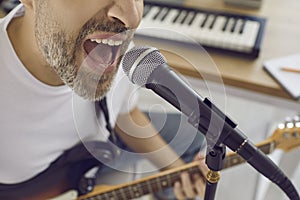 Close up of face of unrecognizable emotional male singer singing into microphone in studio.