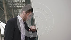 Close-up face of a young dissapointed businessman relying on the wall and sadly shakes his head. Urban city background