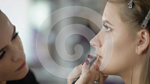 Close up of a face of young female photomodel during make-up process at beauty shop. Professional visagiste is