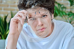 Close-up face of young handsome guy wearing glasses looking at camera