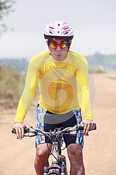 Close up face of young man riding mountain bike in dusty road us