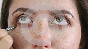 Close up of a face of young professional female photomodel during make-up process at beauty shop. Young visagiste is