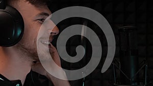 Close up of face of young smiling boy singing song to microphone. Portrait of caucasian man in headphones recording voice. Happy h