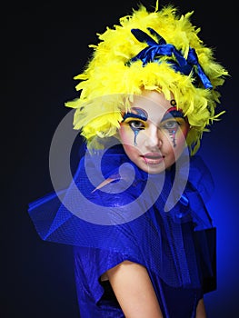 Close up of a face of a young woman with creative visage and yellow wig.