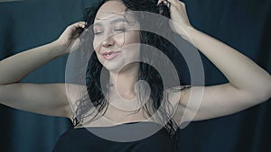 Close-up face of young woman with wet hair. Girl touches her hair in studio