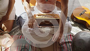 Close up of faceless man playing the Shruti box in healing music session, man sitting in lotus position plays instrument