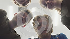 Close up faces of four people talking standing in the circle above the camera. A company of male and female athletes