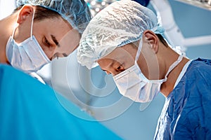 Close-up of the faces of surgeons in a protective mask and cap during an operation. Health care, medical education