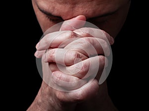 Close up of faithful mature man praying, hands folded in worship to god