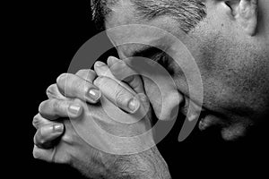 Close up of faithful mature man praying, hands folded in worship to god