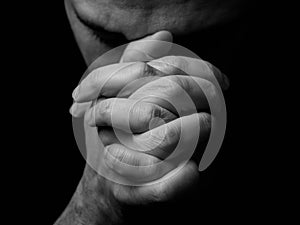 Close up of faithful mature man praying, hands folded in worship to god