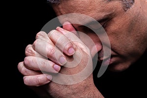 Close up of faithful mature man praying, hands folded in worship to god photo