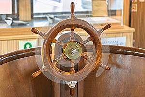 Close-up of a fake varnished wooden ship`s wheel tied with a sailor`s rope.