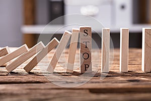 Falling Dominos Stopped By Wooden Blocks Showing Stop Text photo