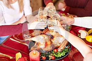 Close-up family clinking glasses on Thanksgiving on a table background. Cheers with champagne. Celebration concept.