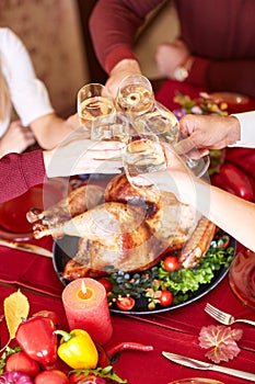 Close-up family clinking glasses on Thanksgiving on a table background. Cheers with champagne. Celebration concept.