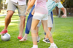 Close Up Of Family Playing Soccer In Park Together