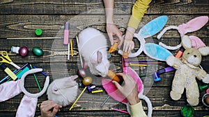 Close-up of the family`s hands that feeds Easter hares and various stationery. Mother, father and son are painting