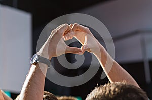 Close up of fan hands showing heart at concert