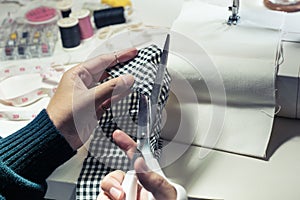 Close up fashion designer cutting cloth with equipment