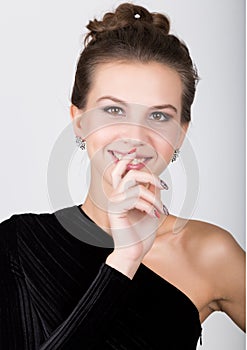 Close-up fashion photo of young lady in elegant black dress, playful woman raised index finger to his lips