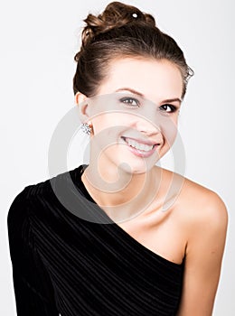 Close-up fashion photo of young lady in elegant black dress, playful woman smiling