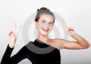 Close-up fashion photo young lady in elegant black dress, playful woman smiling and shows a sign of peace