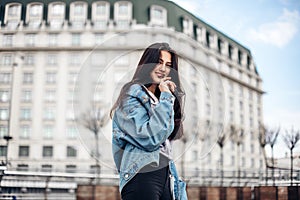 Close up fashion street stile portrait of pretty girl in fall casual outfit walking in city. Beautiful brunette or student