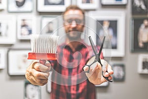 Close up of fashionable hipster hairdresser holding neck brush and scissors