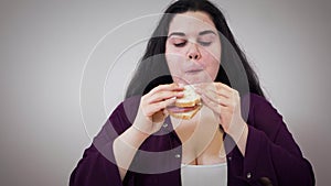 Close-up of fat Caucasian girl chewing sandwich. Obese young woman eating unhealthy food. Obesity, unhealthy lifestyle