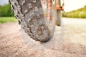 Close-up of fat mountain bike tire on dirty road. Fat bike wheel. Summer outdoor activity.