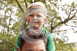 Close Up Of Father Carrying Son On Shoulders On Walk By River