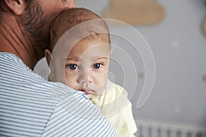 Close Up Of Father Comforting Newborn Baby Son In Nursery